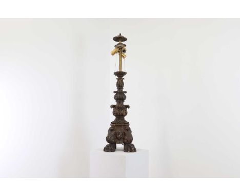 A rococo-style carved wooden table lamp, 19th century, of stepped foliate form with paw feet, converted from an altar candles