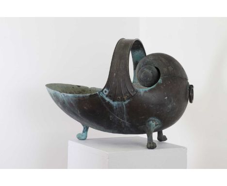 A copper coal scuttle in the form of a nautilus shell,19th century, with a looping handle and raised on paw feet,51cm wide37c