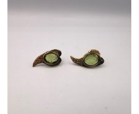 A pair of modern 9ct yellow gold and peridot stylised leaf stud earrings, each earring set with an oval mixed cut peridot wit