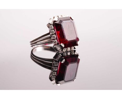 A rubellite and diamond halo ring, consists of an emerald-cut rubellite of 15.4 x 12.9 mm, claw set to a surround with brilli