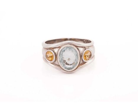 A three-stone ring centrally set with an oval aquamarine and flanked by two round citrines, to a tapering shank with rolled r