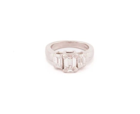 An emerald-cut diamond trilogy ring in platinum, featuring three graduated emerald-cut diamonds in claw settings, to a thick 