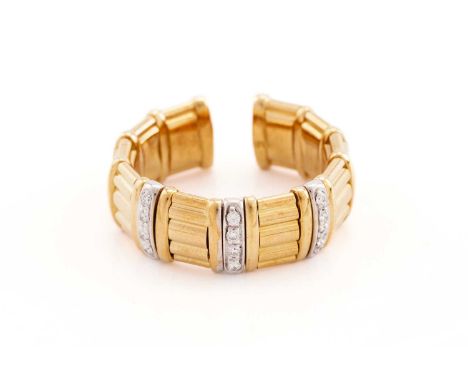 A two-toned cuff ring set with cubic zirconias, comprises reeded sections with gem-set intervals in yellow and white metal, I