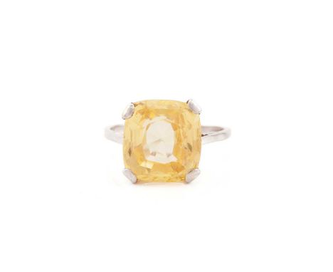 A yellow sapphire solitaire ring, presenting a cushion-cut yellow sapphire with a light orangey-yellow colour approximately m