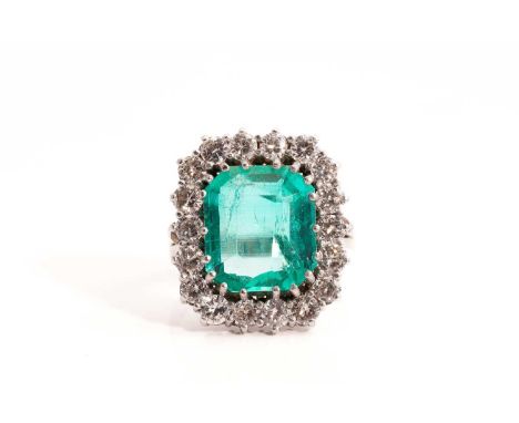 An emerald and diamond entourage ring, featuring a hexagonal step-cut emerald of 13.0 x 11.5 mm, encircled by brilliant-cut d