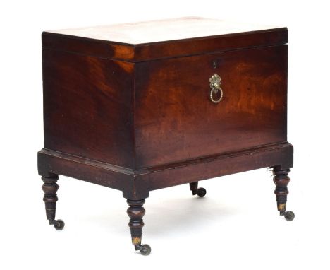 A George III mahogany cellarette, the hinged caddy top opening to a divided interior, raised on turned legs with brass caster