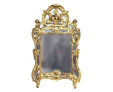A late 18th century Continental carved giltwood wall mirror, the rectangular central plates surrounded by shaped plates and t