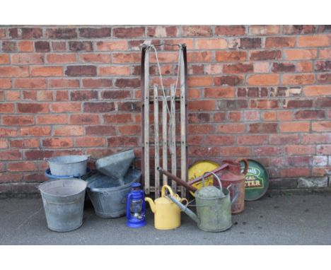 A collection of galvanized and enamel kitchen and garden items, to include a red watering can, two other watering cans, a lam