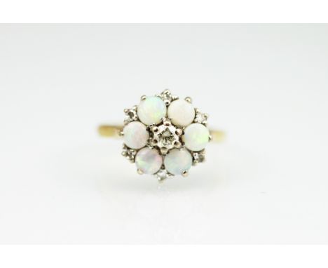 An opal and diamond set circular cluster ring, designed as a central diamond surrounded by six opals and interspersed with si