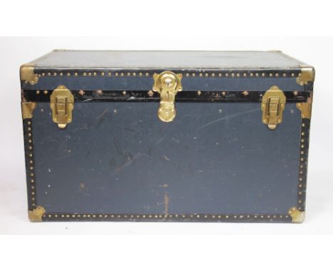 A large vintage metal bound steamer travelling trunk, with locking mechanism, hinged lid and vacant interior along with two c