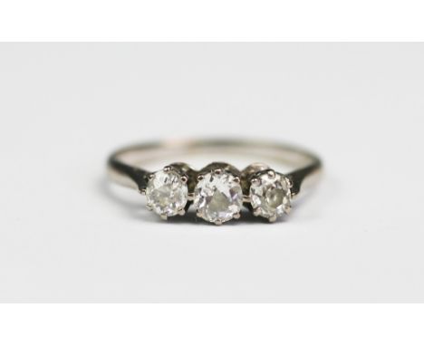 A three stone diamond ring, the three old brilliant cut, graduated diamonds, each claw set in white metal to the tapering sho