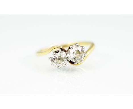 A two stone diamond ring, the two old, mixed cut diamonds within cross-over setting, claw set in white metal to the tapering 