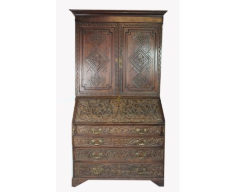 A George III and later carved oak bureau bookcase, with two panelled doors above a fall enclosing a fitted interior over four