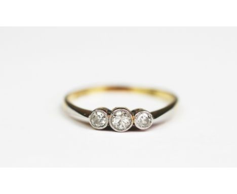 A three stone diamond ring, the three graduated diamonds, each within millegrain collet, white metal setting, to the tapering