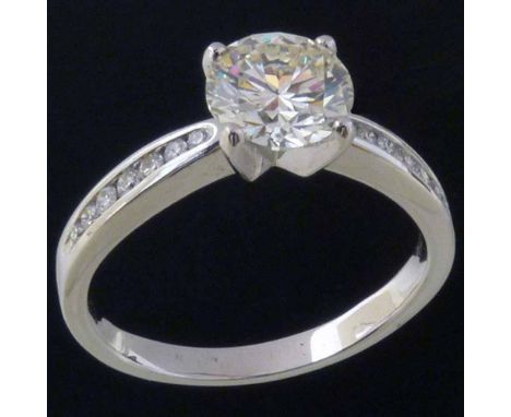 Round brilliant diamond, 2.17ct, in a raised setting on channel set diamond shoulders in a 750 white gold shank, ring size U,