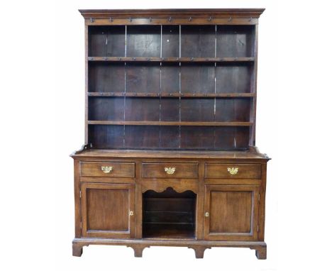 19th century oak dresser, ogee mould above three shelves with an array of cup hooks, pine boarded back, base with three friez