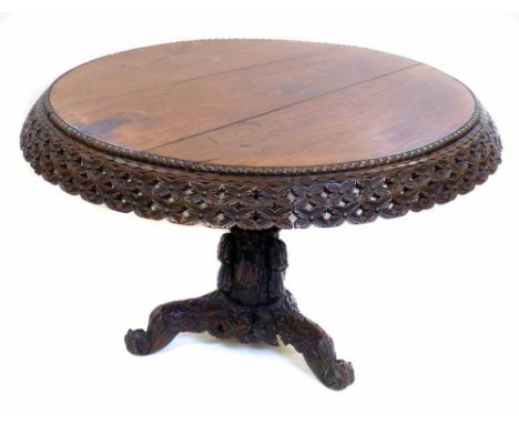 Late 19th century Burmese rosewood centre table, two plank circular top with deep pierced and carved floral frieze, supported