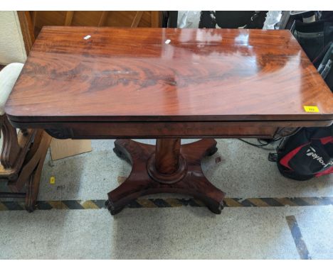 A Regency rosewood fold over card table, leaf carving to the frieze, plain tapering column, on quatrefoil base, with carved, 