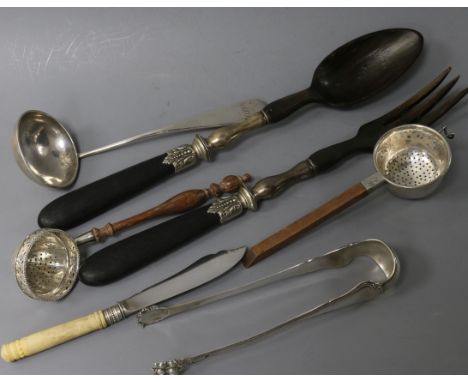 A pair of white metal mounted salad servers, two silver tea strainers, a pair of sugar tongs, a cream ladle & a butter knife 