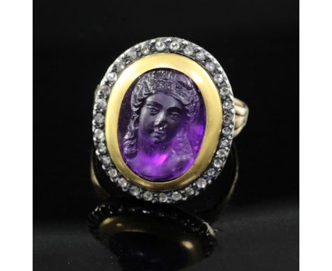 A 19th century amethyst glass? oval cameo ring, with rose cut diamond set border, (adapted?), size M.