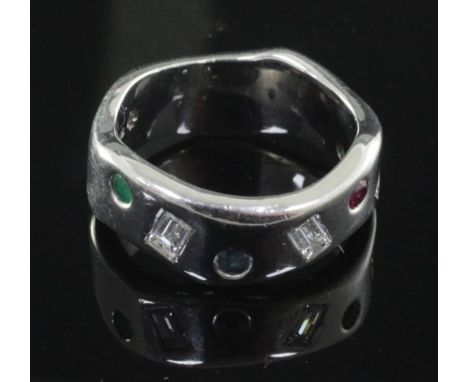 A modernist wavy design 18ct white gold, emerald, ruby, sapphire and baguette cut diamond gypsy set ring, size R.