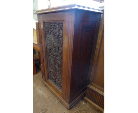 A Vintage Oak Carved Cupboard. The cupboard having two shelves with carved single door and panelled sides and top, on ball fe