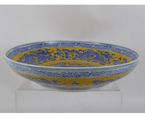 A Contemporary Blue and Yellow Chinese Ceramic Bowl, depicting chasing dragons, marks to base, approx 40 cms dia. 
