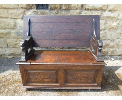 A Carved Mahogany Monk's Bench, with lion supports, storage cupboard beneath, label reads "Collyer's Home Furnishers, Old Taf