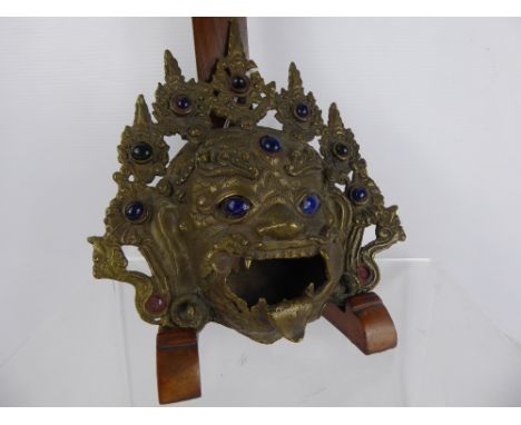 A Tibetan Incense Burner, depicting the mask of Mahakala on tripod base, with blue glass to eyes and headdress, approx 20 x 1