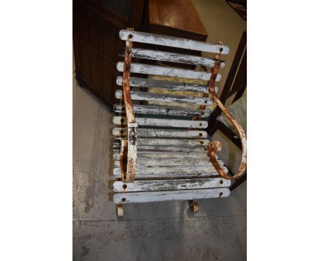 A vintage garden chair having slatted wooden seat and scrolled metal arms and feet.