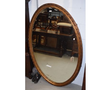 A late 19th or early 20th Century large giltwood/gesso wall mirror of oval form, having lozenge bead and husk mouldings, curr