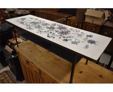 A vintage coffee table, similar to Piper, ply and laminate top having foliate decoration, metal frame , approx. 113 x 37cm