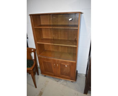 A vintage mid stain bookcase by Ercol, having glazed upper section with two adjustable shelves and sliding doors, having doub
