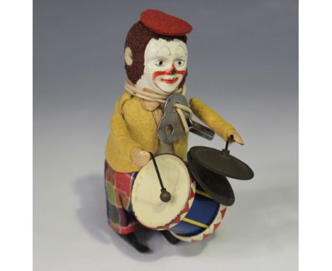 A Schuco clockwork clown playing a drum and cymbals, wearing a red beret, yellow jacket and check trousers, height approx 11c