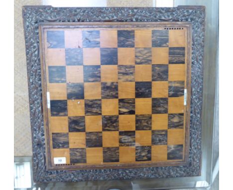An early 20thC profusely foliate carved oak chess board, on stepped bracket feet  24''sq       CA