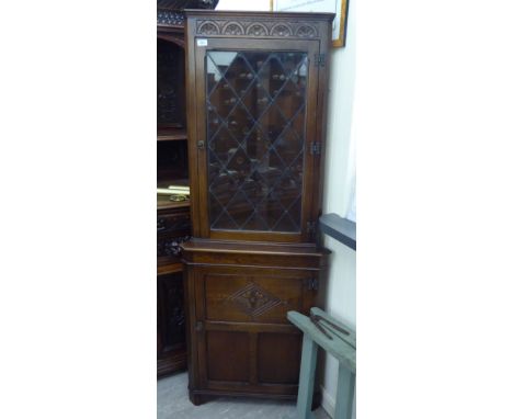 A Jaycee stained oak finished corner cabinet with a glazed door, over a panelled door, raised on bracket feet  74''h  24''w  