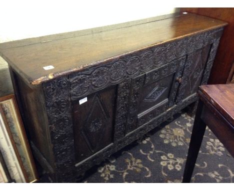 A 17th century oak coffer (with later adaptations), the panelled front with carved floreat decoration, central cupboard door 