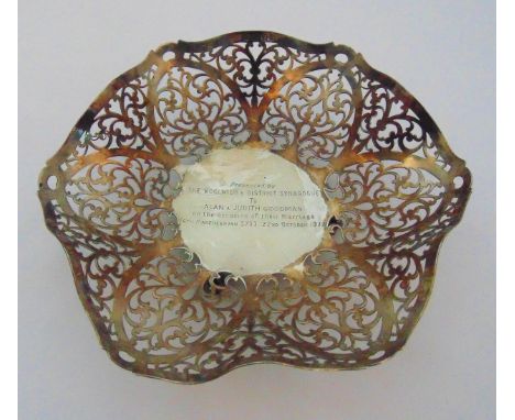 A hallmarked silver pierced shaped circular fruit dish with presentation engraving on three ball and claw feet, London 1971, 