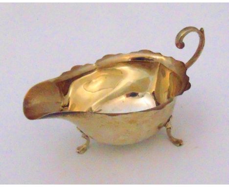 A hallmarked silver sauce boat of customary form with flying double scroll handle, all on three pad feet, Birmingham 1930, ap