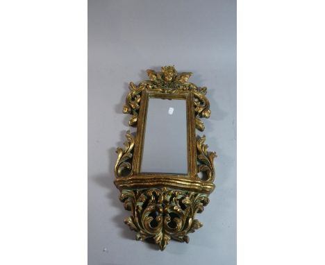 A Reproduction Gilt Framed Wall Hanging Mirror with Shelf, Ornate Pierced Surround and Cherub Bust Finial, 58cm High 