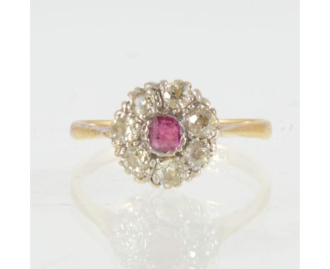 A ruby and diamond cluster ring, a small round cut ruby surrounded by seven old cut diamonds, in a yellow and white metal mou