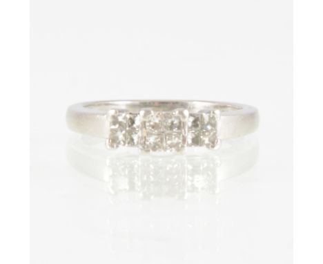 A Princess cut diamond ring, the twelve diamonds arranged in groups of four giving the impression of a three stone ring in an