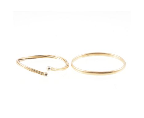 Two modern yellow metal bangles, a 9 carat yellow gold 5mm wide plain hollow sprung bangle, approximate weight 6.3gms, a yell