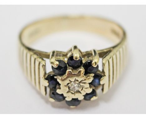 A 9ct gold ring set with a diamond surround by eight sapphires, gross wt. 3.4g, size J/K.