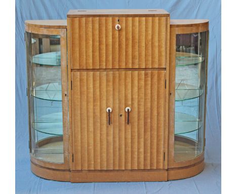 An Art Deco bird's eye maple cocktail cabinet attributed to Harry & Lou Epstein, the fold out mirrored interior bar above rib