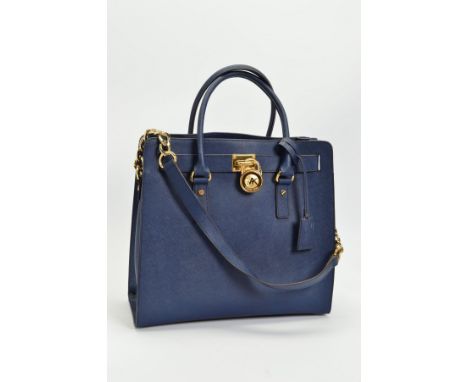 A MICHAEL KORS HAMILTON NAVY HANDBAG, the large leather tote with gold tone hardware, padlock and key in cover, part chain sh