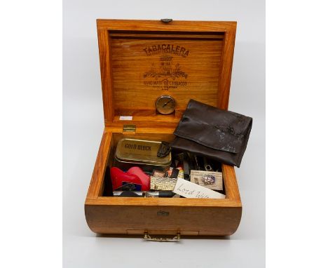 A Tabacalera humidor with hygrometer containing a quantity of matchbooks and lighters, some of the matchbooks bearing the nam