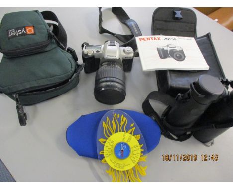 A Pentax MZ50 camera and travel case, modern Minox binoculars and a New Zealand sun dial 