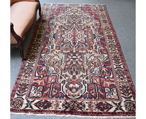 Bakhtiari Carpet, the ivory field with central burgundy panel centred by a medallion framed by spandrels and ivory borders, 3