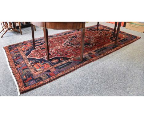 Hamadan Regional Rug, the raspberry field of angular vines centred by a medallion, framed by spandrels and indigo borders, fl